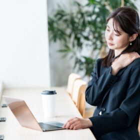 デスクワーク中に首の後ろに手をあてる女性。肩こりの原因を研究データから検証する記事のアイキャッチ